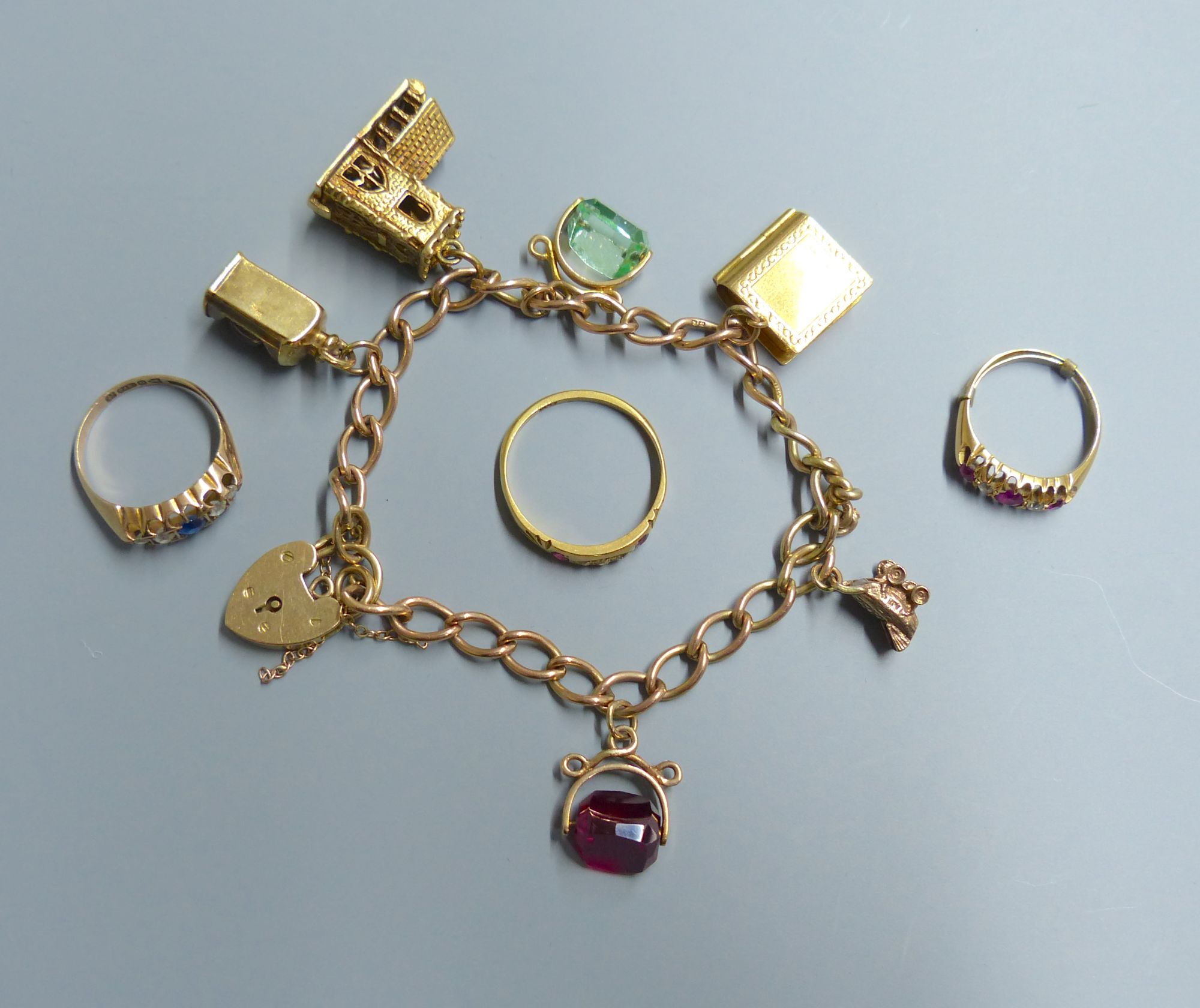 A 9ct gold charm bracelet, hung with six assorted charms including 9ct gold and 3 rings.